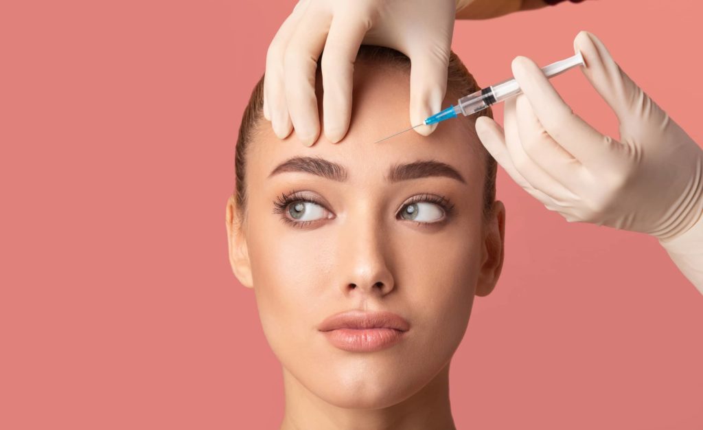 young-woman-receiving-botox-beauty-injection-in-forehead young-woman-receiving-botox-beauty-injection-in-forehead